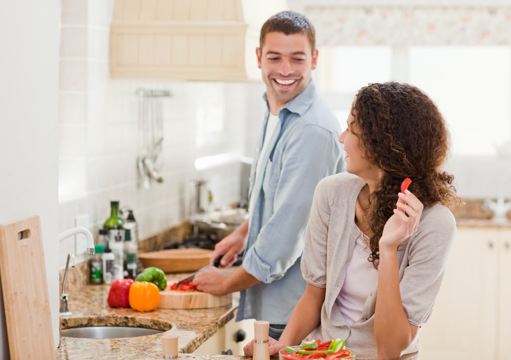 Beautiful woman looking at her husband who is cooking at home