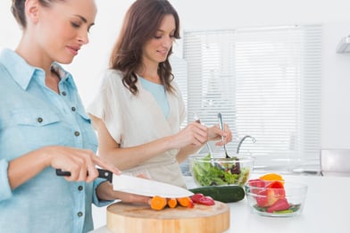 Women preparing salad together  in the kitchen