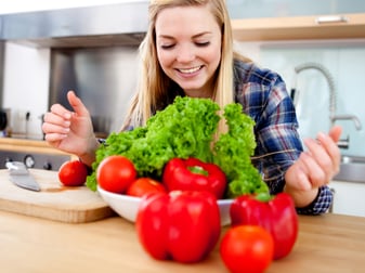 Young female cook making a fresh salad with organic vegetables