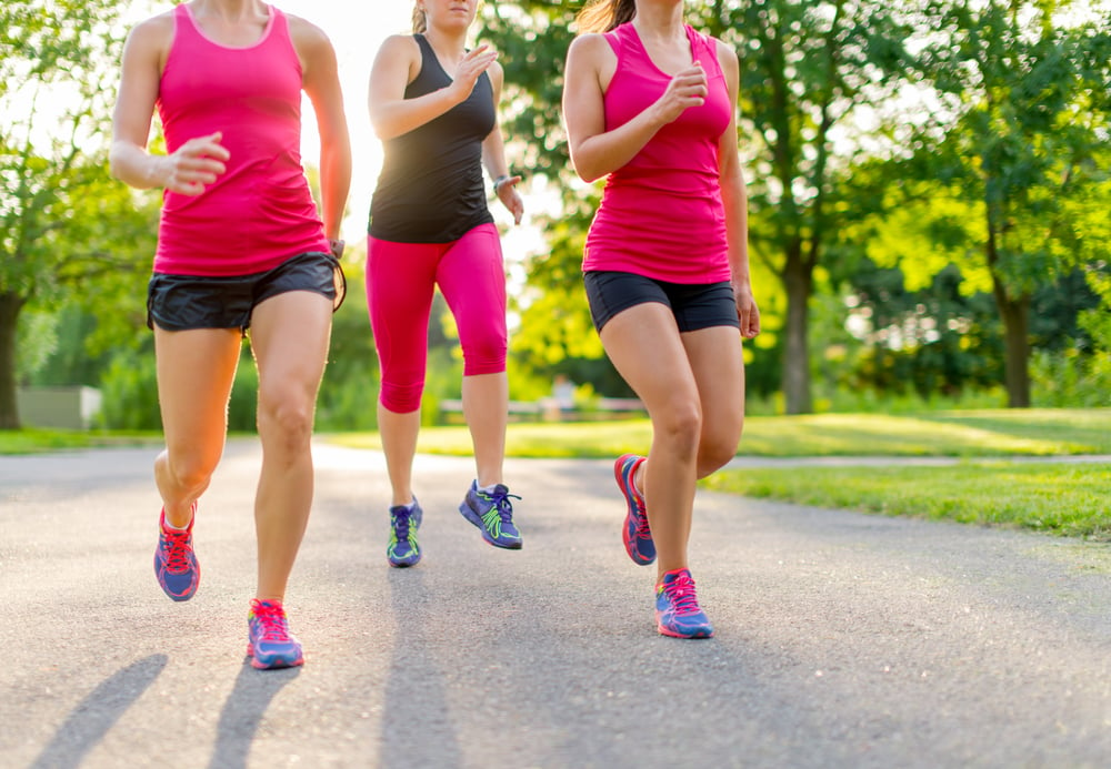 group of healthy girls running outdoors at sunset with lens flare.